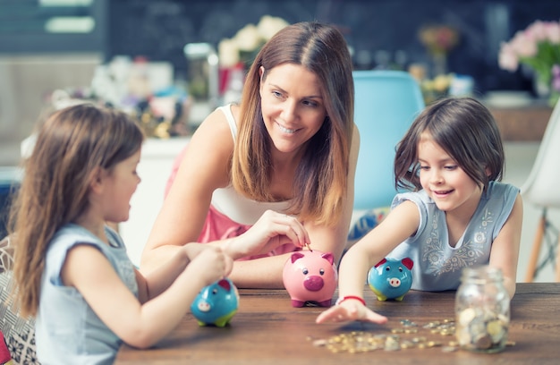 La figlia della mamma della famiglia felice risparmia i risparmi futuri di investimento del salvadanaio dei soldi.