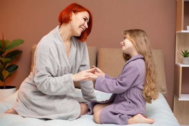 La figlia fa la mamma manicure a casa sul letto