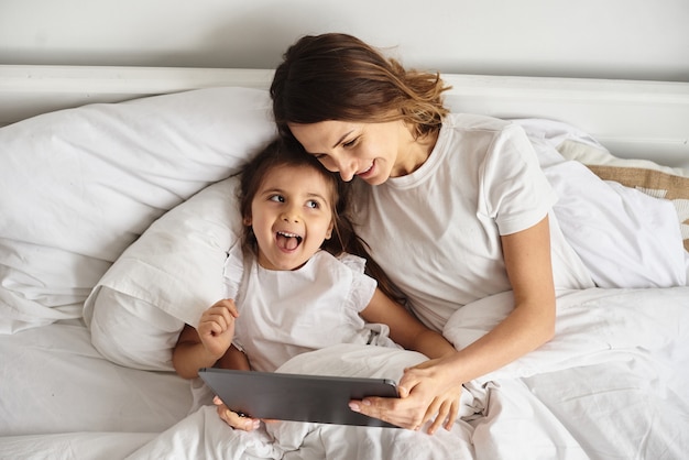 La figlia gioca con mamma e gatto mentre la mamma lavora al computer