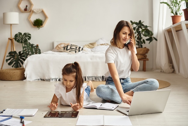 La figlia gioca con mamma e gatto mentre la mamma lavora al computer