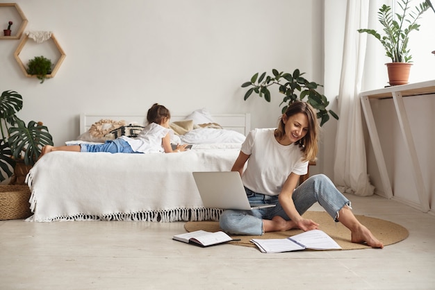 La figlia gioca con mamma e gatto mentre la mamma lavora al computer