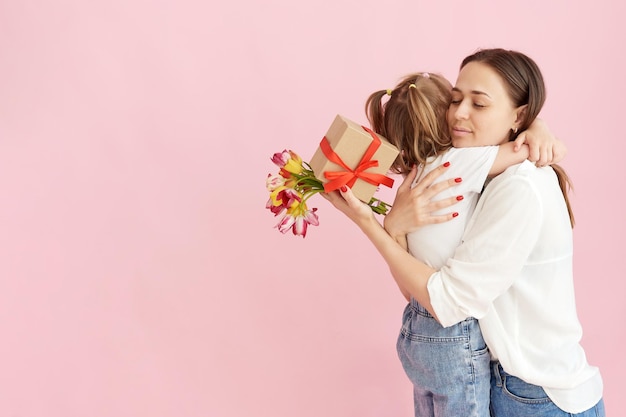 La figlia regala alla mamma un bouquet di tulipani rossi su sfondo rosa