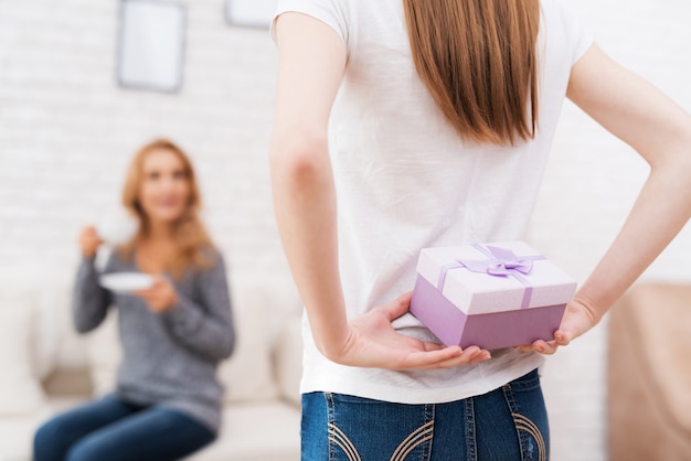 La figlia sorridente dà il regalo della madre in piccola scatola.