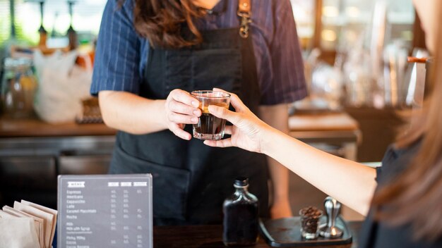 La fine della mano femminile sta prendendo il caffè caldo dal barista