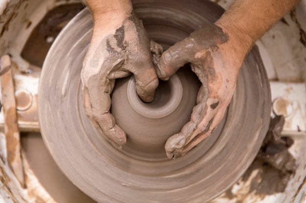 La fine sulla vista del dettaglio ad un artista fa le terraglie dell&#39;argilla su una ruota di rotazione