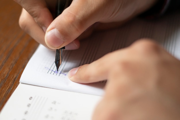 La fine sulle mani dello studente annota le note di musica su classe a scuola