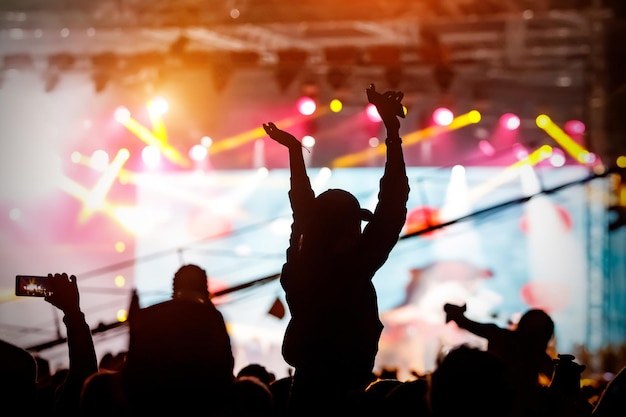 La folla con le mani in alto si gode un concerto musicale Silhouette di un fan sullo sfondo del palco