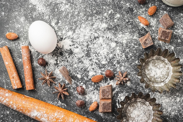 La forma del cupcake di concetto di cottura e gli ingredienti alimentari su uno sfondo scuro si preparano per la cottura della vista dall'alto