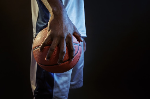 La forte mano del giocatore di basket tiene la palla. Baller maschio professionista in abbigliamento sportivo che gioca a giochi sportivi, sportivo alto