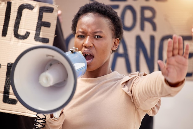 La forza è ciò di cui abbiamo bisogno Inquadratura di una giovane donna con la mano alzata che parla attraverso un megafono durante una protesta