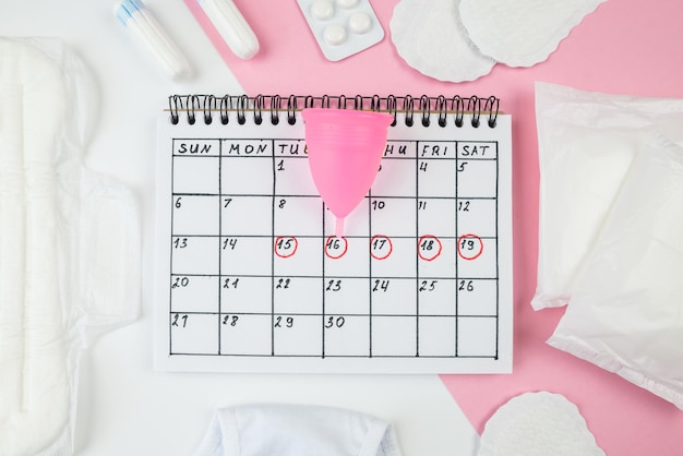 La foto dall'alto del calendario rosso segna le mutandine assorbenti e tamponi per coppette mestruali su whi isolato