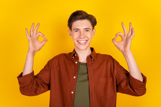 La foto del giovane bel ragazzo di buon umore mostra le dita okey simbolo buon lavoro perfetto isolato su sfondo di colore giallo