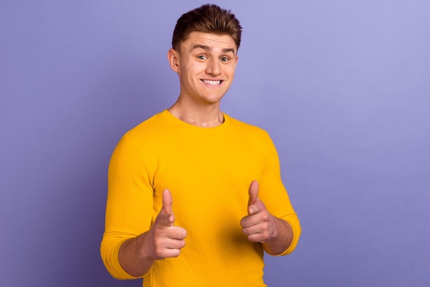 La foto del giovane ragazzo allegro indica la scelta delle dita scegliere la pubblicità isolata su sfondo di colore viola
