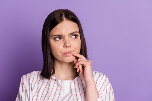 La foto del mento del tocco del dito della giovane donna pensa che sembra un piano con la mentalità dello spazio vuoto isolato su uno sfondo di colore viola