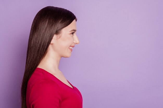 La foto del profilo di una signora allegra e attraente sembra uno spazio vuoto con un sorriso raggiante su sfondo viola