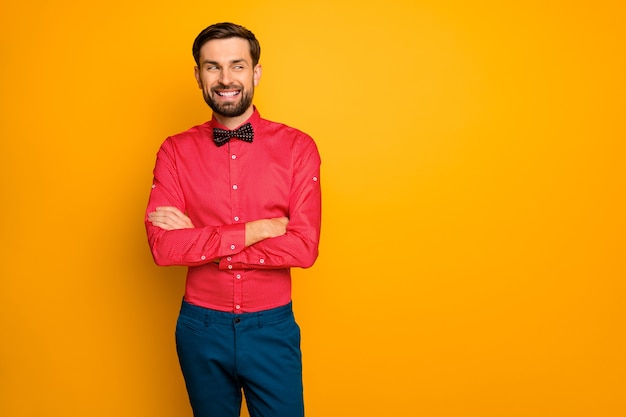 La foto del ragazzo attraente di affari ha attraversato la persona amichevole che osserva lo spazio vuoto laterale indossa la camicia rossa alla moda con i pantaloni blu del legame di arco nero