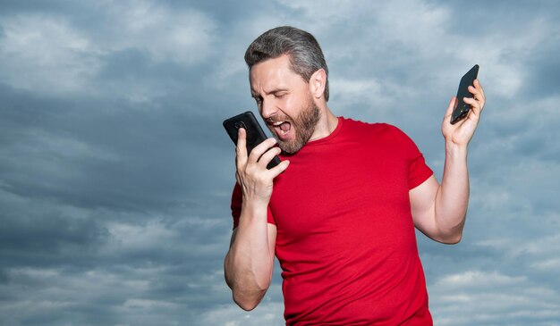 La foto dell'uomo arrabbiato che grida ha una conversazione telefonica l'uomo ha una conversazione telefonica sullo sfondo del cielo