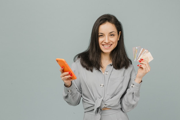 La foto della femmina sorridente sveglia tiene i cads di credito e dello smartphone