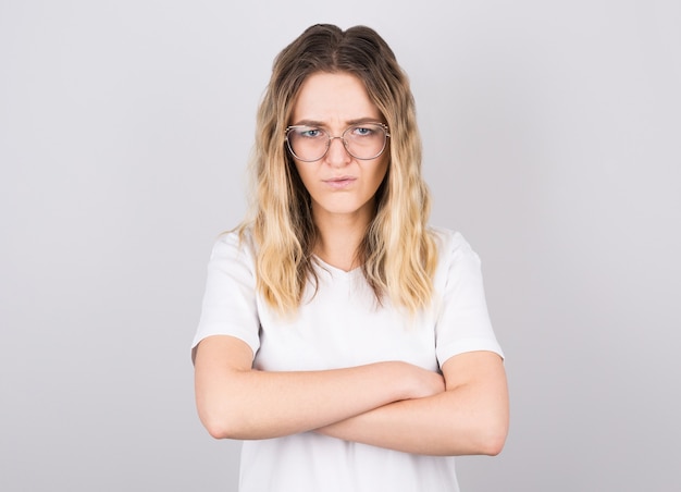 La foto della giovane femmina caucasica scontrosa arrabbiata si è vestita con indifferenza mantenendo le braccia piegate