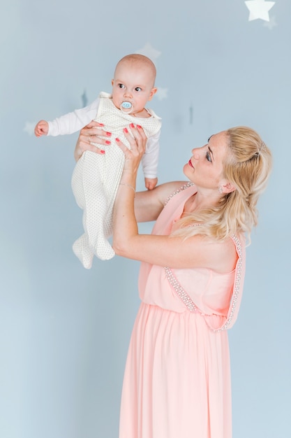 La foto della madre gioca e vomita un bambino nella stanza dei bambini sullo sfondo del muro blu