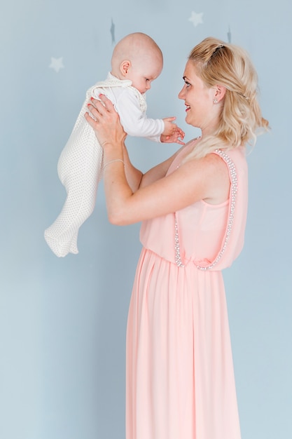 La foto della madre gioca e vomita un bambino nella stanza dei bambini sullo sfondo del muro blu