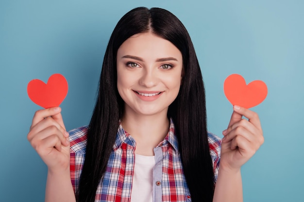 La foto della ragazza mostra l'amore romantico del giorno di San Valentino del cuore di piccola forma isolato sopra il fondo di colore del turchese