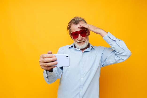 La foto di camicie blu da vecchio in pensione con gli occhiali prende uno sfondo isolato selfie