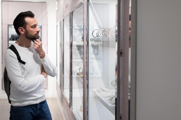 La foto di un bell'uomo bruno adulto con una felpa bianca e uno zaino sceglie un elegante