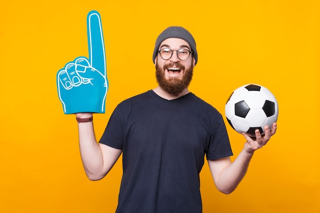 La foto di un uomo che tiene un guanto da ventaglio e un pallone da calcio sorride