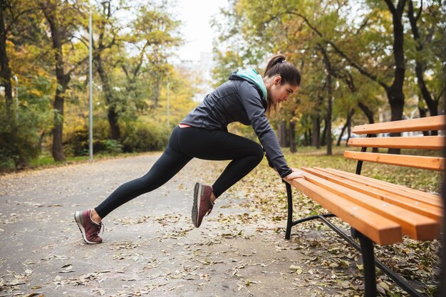 La foto di una bella donna abbastanza giovane abbastanza fitness all'aperto nel parco fa esercizi sportivi.