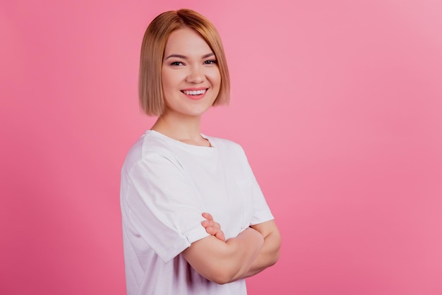 La foto di una donna sicura di sé positiva con le mani giunte indossa una maglietta bianca isolata su sfondo rosa