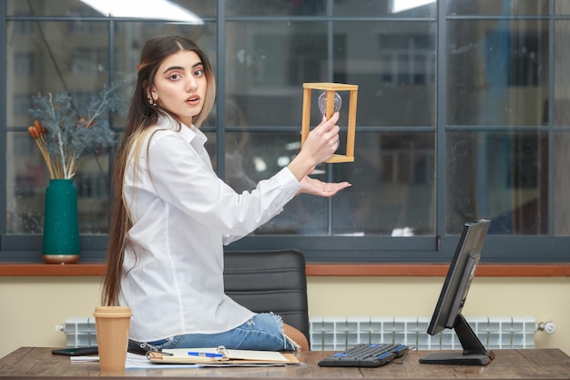 La foto di una giovane e bella signora che tiene la clessidra e guarda la telecamera