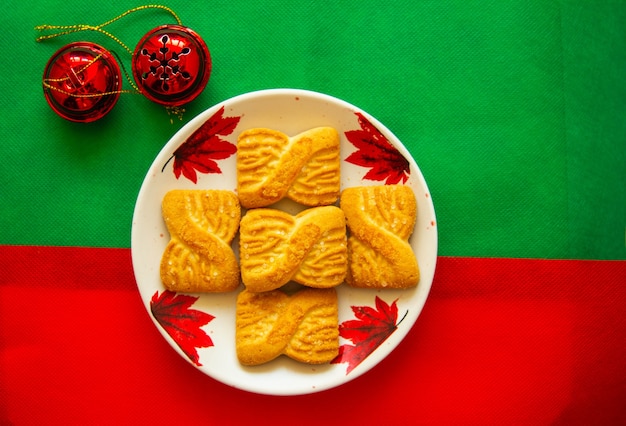 La foto di una pila di biscotti o biscotti di pasta frolla sul piatto con campane rosse. Priorità bassa di giorno nazionale del biscotto. Colazione di Natale per Babbo Natale.