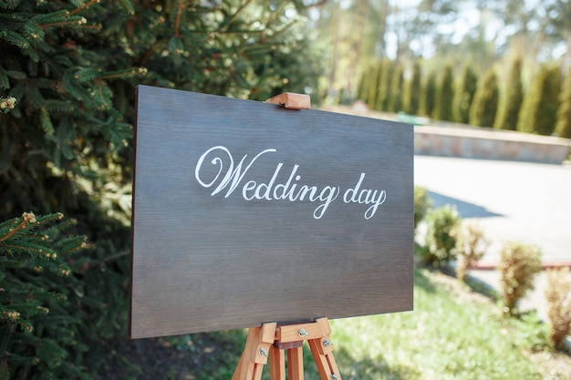 La foto in primo piano della targa in legno con la scritta Benvenuti al matrimonio in piedi in strada