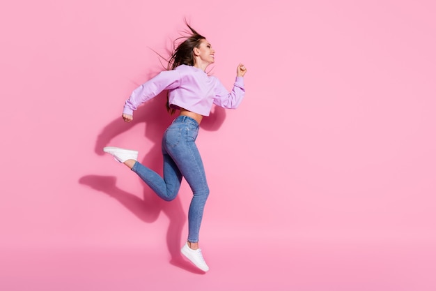 La foto laterale del profilo completo del corpo di una ragazza attiva allegra salta correndo dopo le occasioni di vendita della stagione indossa un pullover elegante e alla moda con scarpe da ginnastica isolato su uno sfondo di colore pastello