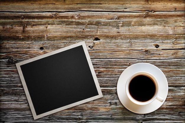 La foto vuota con una tazza di caffè si trova su una tavola di legno