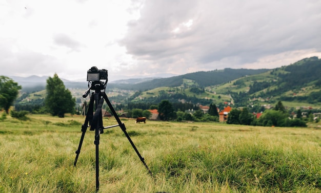 La fotocamera su un treppiede cattura un bellissimo paesaggio di montagna con un villaggio e una foresta