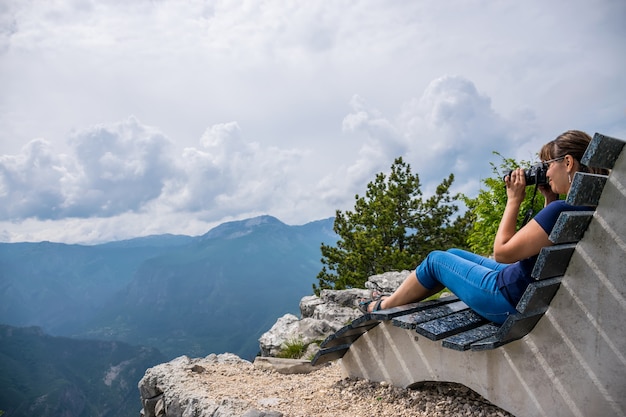 La fotografa si riposa sulla cima della montagna, seduta su un'insolita panchina.