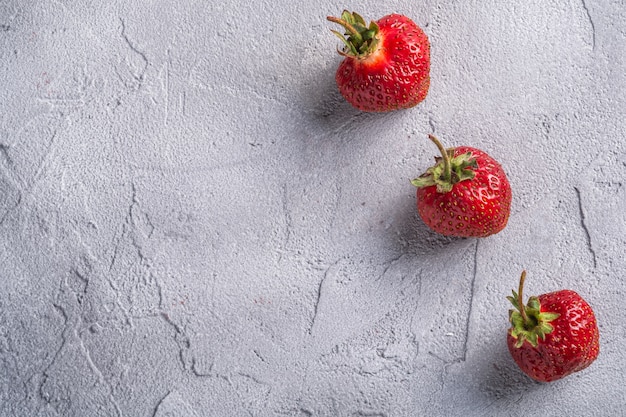 La fragola matura fresca fruttifica nella fila, bacche della vitamina dell'estate su fondo di pietra grigio, spazio della copia di vista superiore