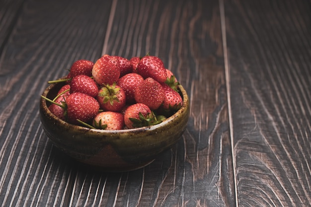 La fragola nel piatto sullo sfondo di legno nero