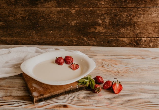 La fragola rossa succosa si trova in un piatto bianco con latte