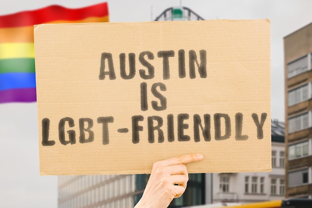 La frase "Austin is LGBT-Friendly" su uno striscione in mano da uomo con una bandiera LGBT sfocata sullo sfondo. Relazioni umane. diverso. Diversi. libertà. Sessualità. Questioni sociali. Società
