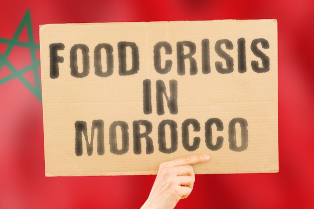 La frase Crisi alimentare in Marocco è su uno striscione nelle mani degli uomini con una bandiera marocchina sfocata sullo sfondo Crisi Finanza Vita Nutrizione Pane Disastro Crollo Problema sociale