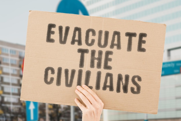 La frase Evacuate the Civilians è su uno striscione nelle mani di uomini con sfondo sfocato Evento Caos Straniero Emigrante Fugitive Force Fight Offense Combat Offensive Disabled Group