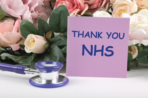 La frase "Grazie NHS" e lo stetoscopio con un bouquet di rose su sfondo bianco Gratitudine al personale sanitario