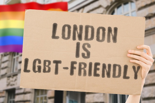 La frase London is LGBTFriendly su uno striscione in mano da uomo con bandiera LGBT sfocata