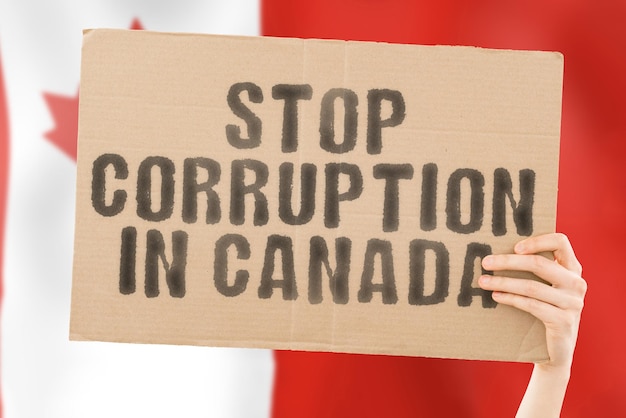 La frase Stop Corruption in Canada su uno striscione in mano maschile con bandiera canadese sfocata sullo sfondo Proibito Prevenire il reato di ricchezza Corruzione Economia politica corruttibile