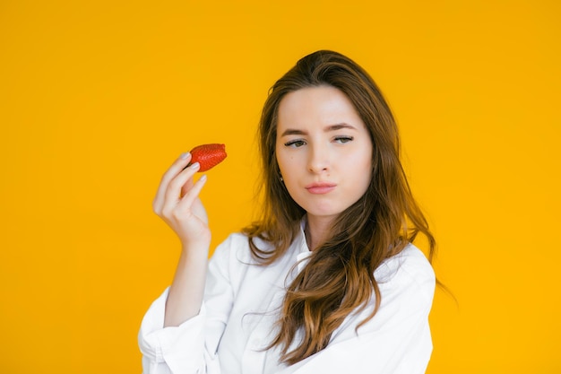 La freschezza viene in rosso Primo piano della bella donna che tiene fragola in mano