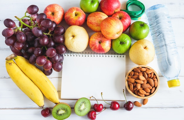 La frutta fresca e misura il nastro con acqua su fondo di legno bianco