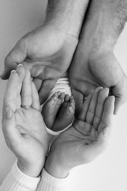 La gamba dei bambini nelle mani dei genitori del padre della madre Piedi di un piccolo neonato da vicino Piccolo piede del bambino Mamma e suo figlio Concetto di famiglia felice Foto in bianco e nero della maternità